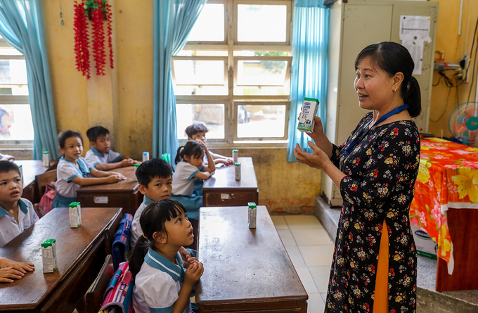 Giáo viên trường Tiểu học Thị trấn Củ Chi (TP HCM) hướng dẫn cho học sinh uống sữa học đường đúng cách vào tháng 6/2020. Ảnh: Quỳnh Trần.