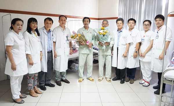 Hai bệnh nhân (ở giữa), nhận hoa chúc mừng từ ban lãnh đạo BVTW Huế.
