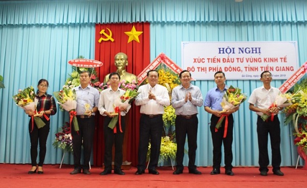 Phó Chủ tích Thường trực UBND tỉnh Tiến Giang Lê Văn Nghĩa (ở giữa) trao hoa lưu niệm cho doanh nghiệp có đóng góp phát triển vùng kinh tế phía Đông tỉnh Tiền Giang.