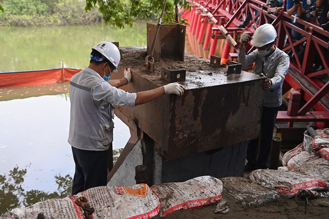 Công nhân dùng máy thủy lực ép khối bê tông xuống đáy hồ