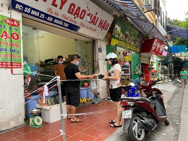 Người dân mua đồ thiết yếu phải đứng ngoài, bảo đảm khoảng cách trong đợt giãn cách xã hội trên địa bàn phường Nghĩa Tân.