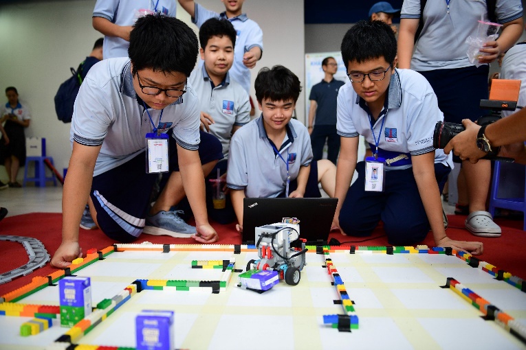 A group of boys looking at a robot

Description automatically generated