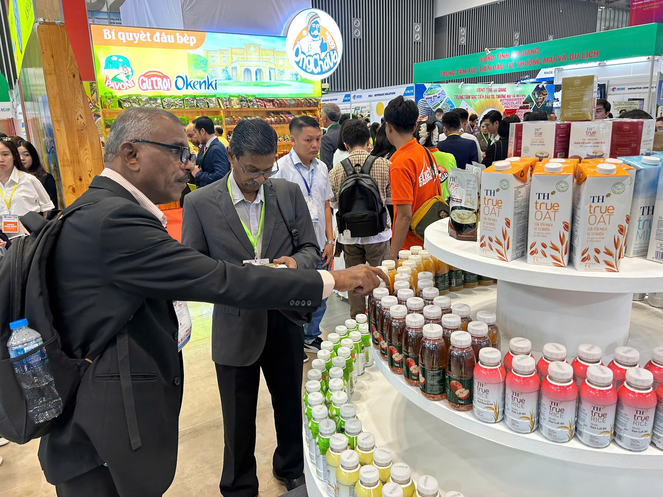 A group of people standing around a display of drinks

Description automatically generated