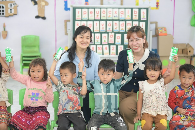 A group of children and a person posing for a photoDescription automatically generated