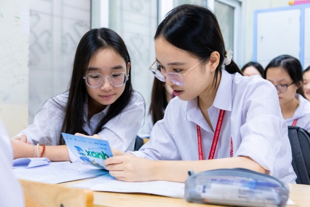 A group of girls looking at a piece of paperDescription automatically generated