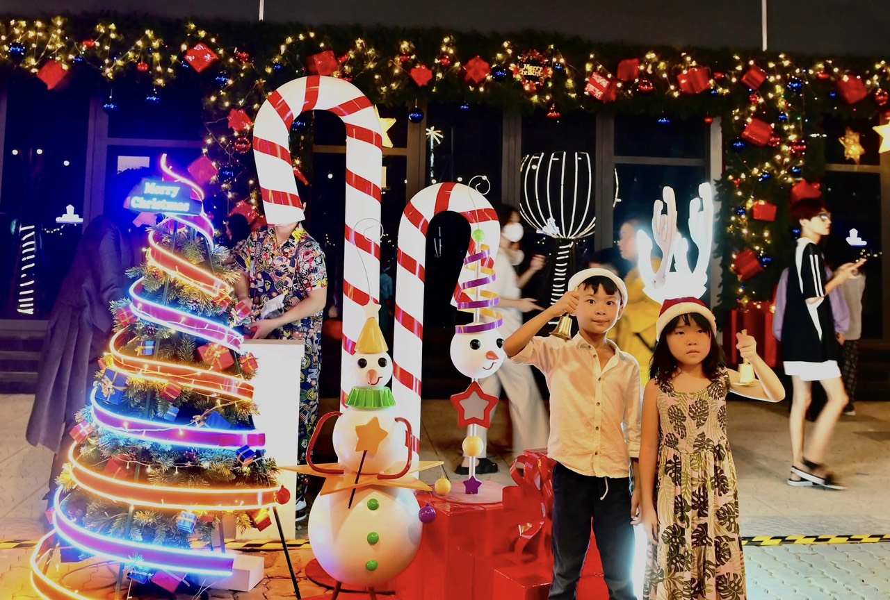 A group of kids standing in front of a christmas display

Description automatically generated