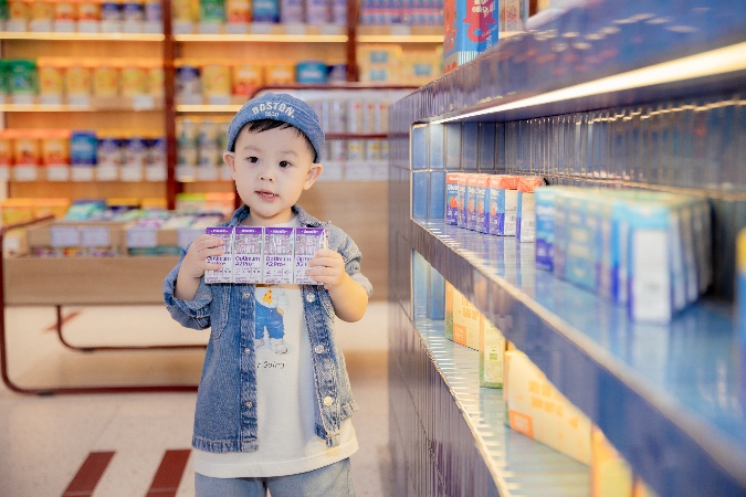 A child holding a box in front of shelvesAI-generated content may be incorrect.