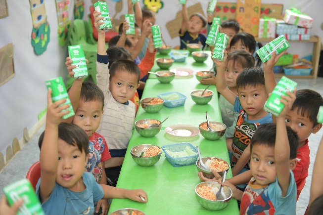 A group of children sitting at a table with foodDescription automatically generated