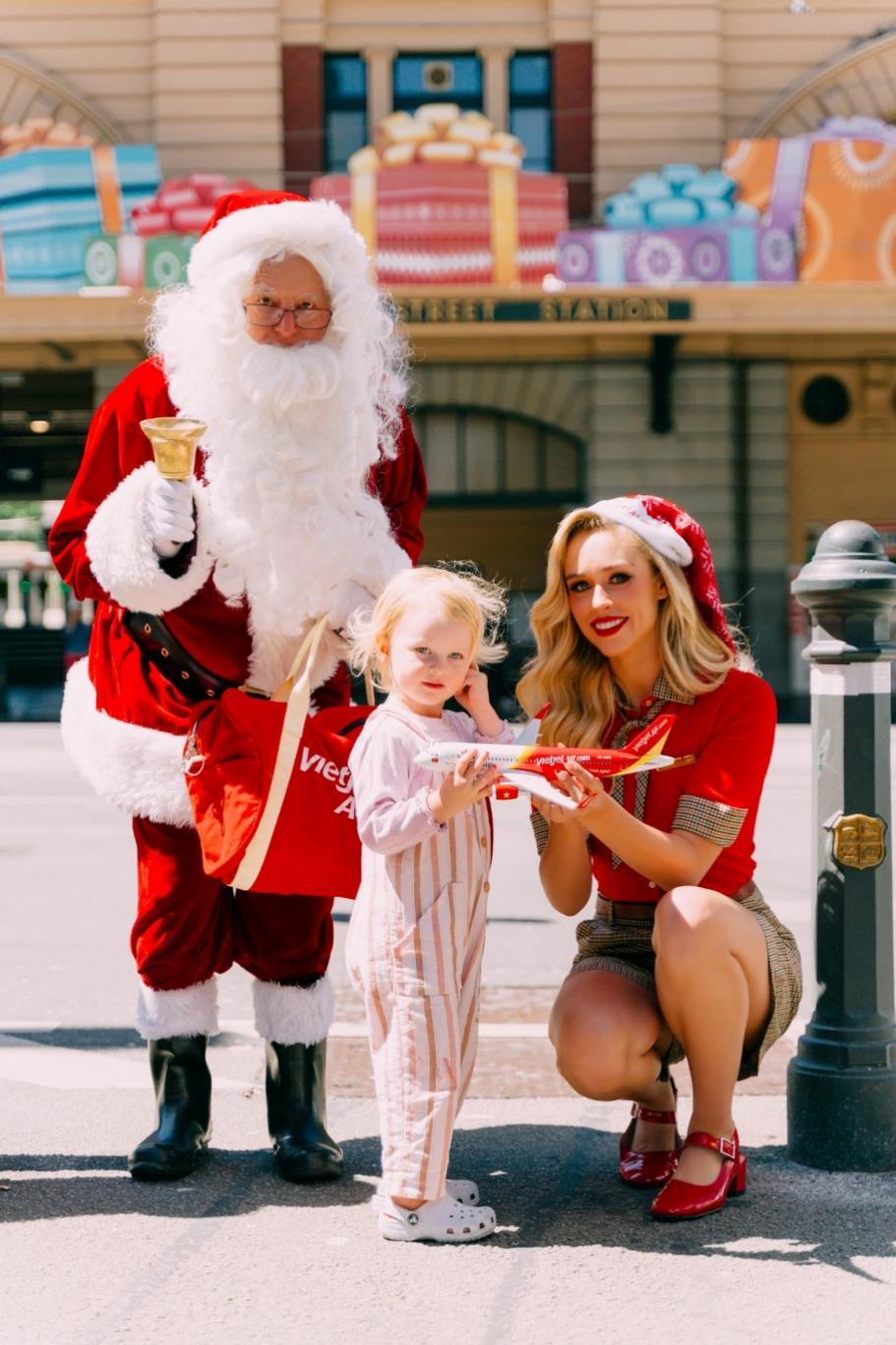 A person and child posing for a picture with santa clausDescription automatically generated