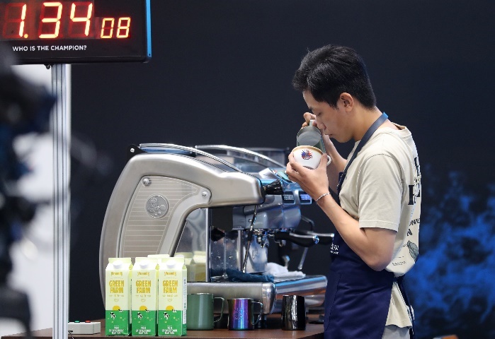 A person standing next to a coffee machineDescription automatically generated