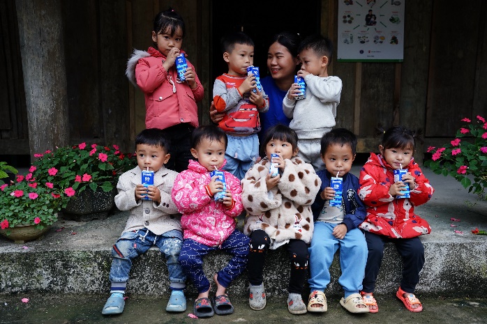 A group of children sitting on a stone ledge holding drinks

Description automatically generated