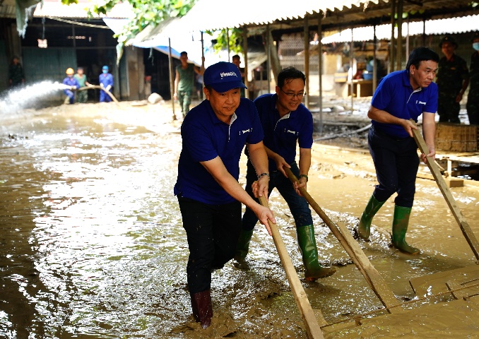 A group of men cleaning a flooded area

Description automatically generated