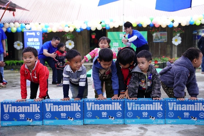 A group of children climbing over a stack of milk boxes

Description automatically generated