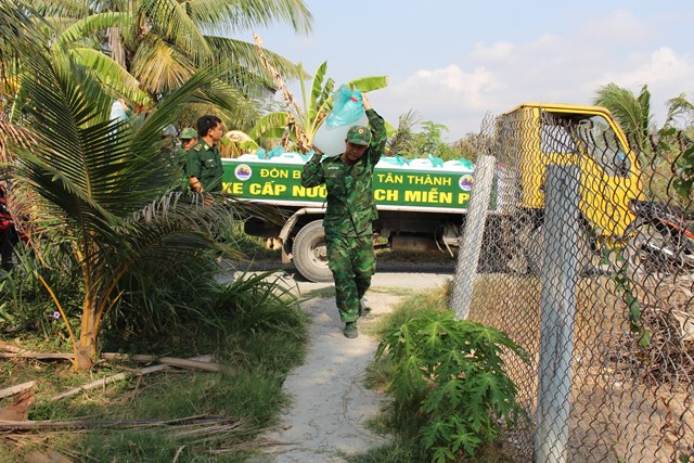 Chiến sĩ biên phòng vác các bình nước mang cấp phát cho các hộ gia đình.  