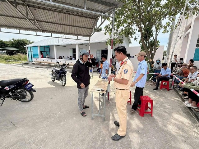 Lực lượng Cảnh s&aacute;t giao th&ocirc;ng hướng dẫn người d&acirc;n l&agrave;m thủ tục trước khi v&agrave;o phần thi s&aacute;t hạch l&aacute;i xe m&ocirc; t&ocirc; tại trung t&acirc;m s&aacute;t hạch.