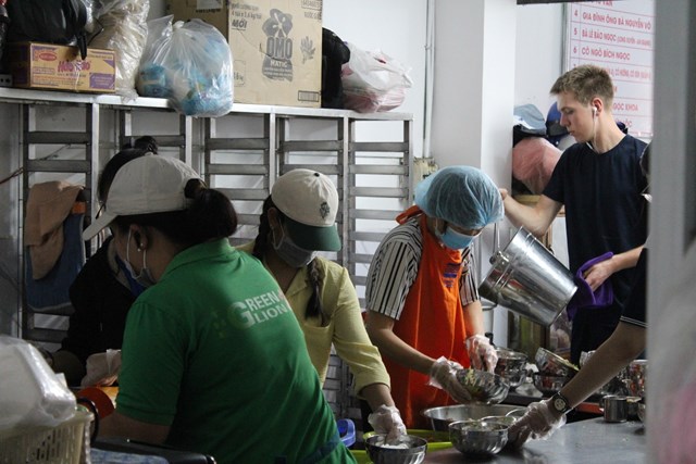 Nh&acirc;n vi&ecirc;n v&agrave; t&igrave;nh nguyện vi&ecirc;n phục vụ c&aacute;c phần ăn theo quy tr&igrave;nh li&ecirc;n tục.