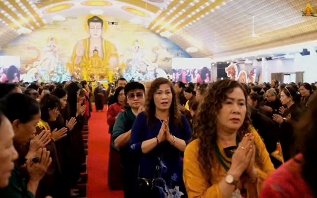 Đại chúng phật tử CLB - G20 Hội Nghĩa tình chợ quán toan thành kính chắp tay và di chuyển trên thảm đỏ trong chính điện Chùa Đỏ, hướng về tượng Phật uy nghi giữa không gian trang nghiêm, rực rỡ ánh vàng của buổi lễ